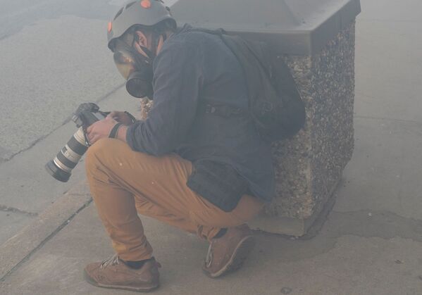 Фотокорреспондент Reuters Карлос Барриа прячется за мусорным баком от государственного патруля штата Миннесота - Sputnik Lietuva