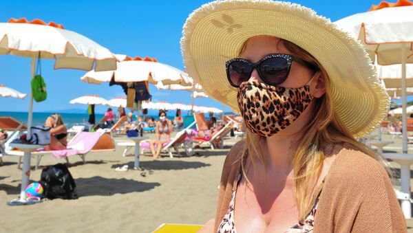 Женщина в защитной маске и солнцезащитных очках на пляже в Кастильоне-делла-Пеская, Италия - Sputnik Литва