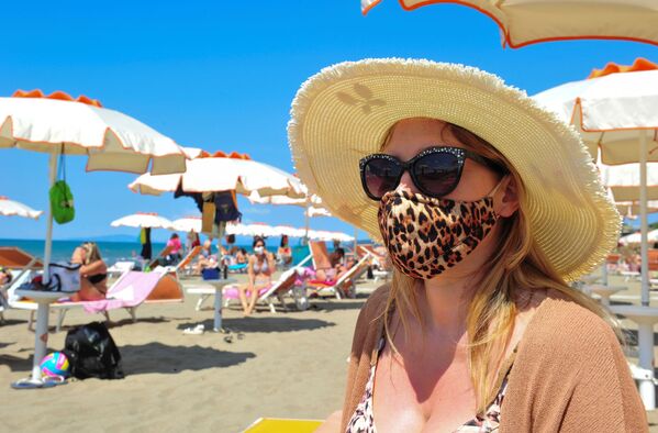 Женщина в защитной маске и солнцезащитных очках на пляже в Кастильоне-делла-Пеская, Италия - Sputnik Литва