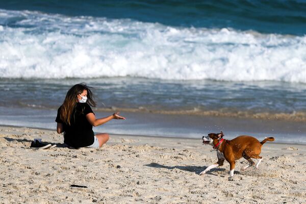 Девушка во время игры с собакой на пляже в Рио-де-Жанейро, Бразилия  - Sputnik Lietuva