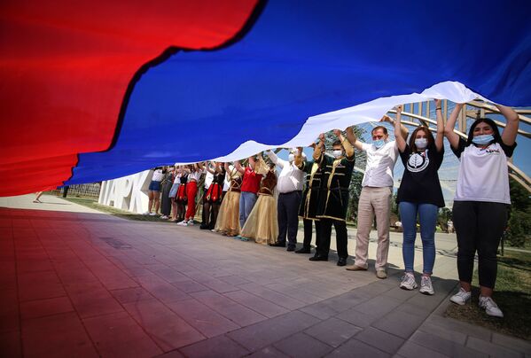 Участники празднований Дня России держат российский флаг в парке Дружбы города Георгиевска Ставропольского края - Sputnik Литва