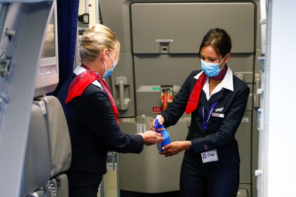 Стюардессы в медицинских масках обрабатывают руки антисептическим гелем в салоне самолета в международном аэропорту Брюсселя - Sputnik Lietuva