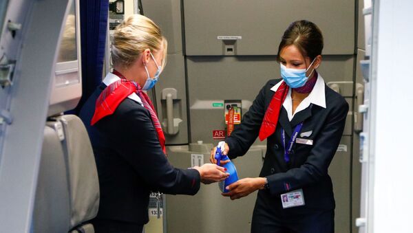 Стюардессы в медицинских масках обрабатывают руки антисептическим гелем в салоне самолета в международном аэропорту Брюсселя - Sputnik Литва