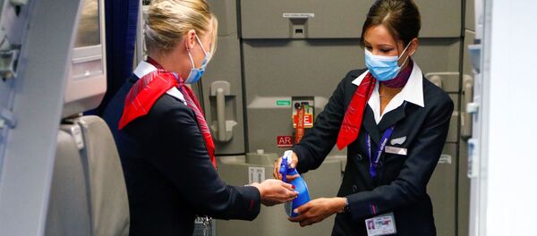 Стюардессы в медицинских масках обрабатывают руки антисептическим гелем в салоне самолета в международном аэропорту Брюсселя - Sputnik Литва