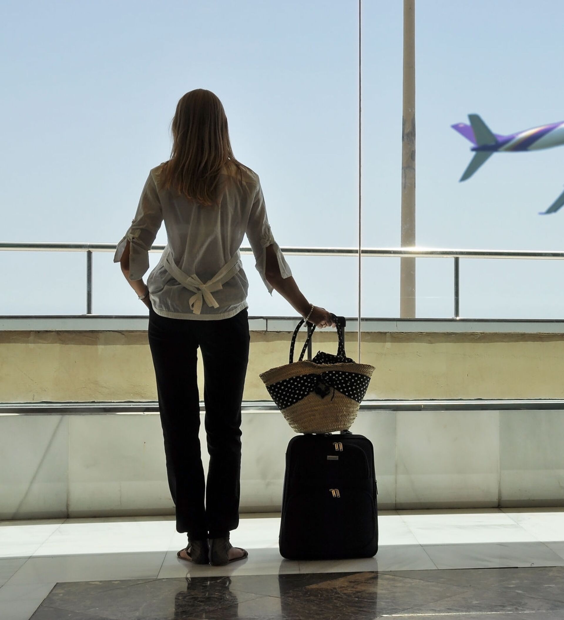 Девушка с чемоданами у аэропорта