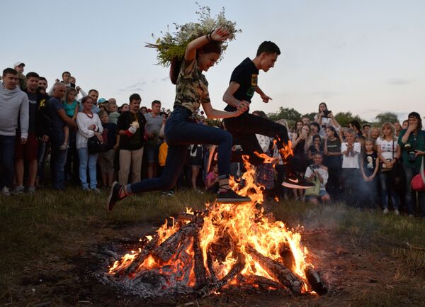 Девушка и юноша прыгают через костер во время праздника Ивана Купалы  - Sputnik Литва