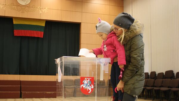 Избирательница с ребенком опускают бюллетень в урну - Sputnik Литва