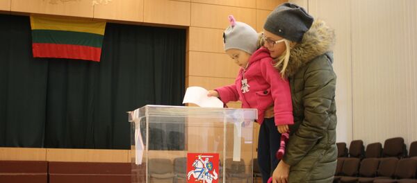 Избирательница с ребенком опускают бюллетень в урну Избирательница с ребенком опускают бюллетень в урну - Sputnik Lietuva