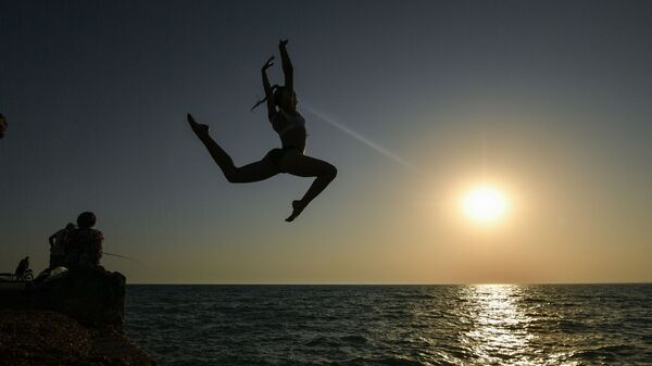 Девушка во время прыжка с пирса на пляже в посёлке городского типа Новофёдоровка Сакского района - Sputnik Lietuva