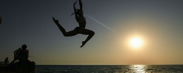 Девушка во время прыжка с пирса на пляже - Sputnik Литва