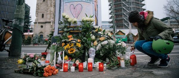 Девушка зажигает свечу недалеко от места теракта в Берлине, где 19 декабря мужчина на грузовике врезался в посетителей рождественской ярмарки Девушка зажигает свечу недалеко от места теракта в Берлине, где 19 декабря мужчина на грузовике врезался в посетителей рождественской ярмарки - Sputnik Литва