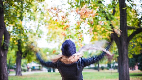 Девушка подбрасывает осеннюю листву в парке - Sputnik Lietuva