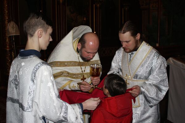 Священник причащает ребенка - Sputnik Lietuva