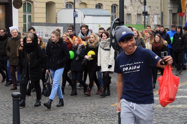 Турист из Азии снимает себя на видеокамеру на фоне молодежного марша - Sputnik Lietuva