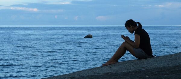 Девушка сидит в телефоне на берегу - Sputnik Литва