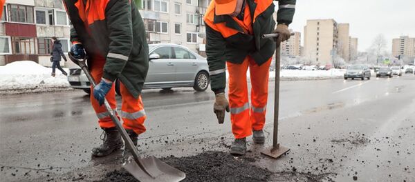 Дорожные работники заделывают дыру в асфальте - Sputnik Литва