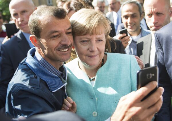 Канцлер Германии Ангела Меркель сфотографировалась с беженцем во время посещения лагеря для мигрантов в Берлине - Sputnik Литва