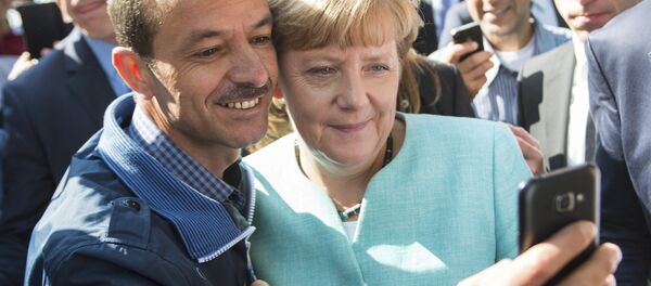 Канцлер Германии Ангела Меркель сфотографировалась с беженцем во время посещения лагеря для мигрантов в Берлине - Sputnik Литва
