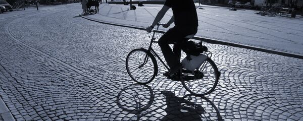 Велосипедист ночью едет по брусчатке Велосипедист ночью едет по брусчатке - Sputnik Lietuva