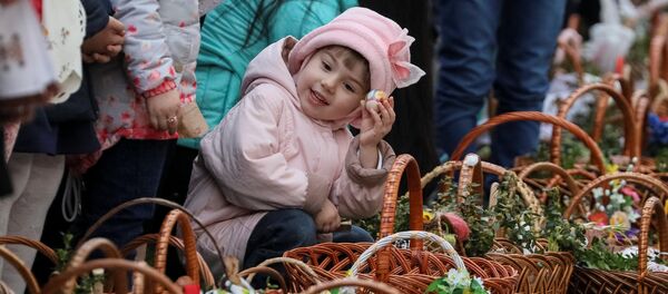 Девочка ждет возле церкви благословения пасхальных куличей и яиц перед богослужением в Пустомытах, Украина Девочка ждет возле церкви благословения пасхальных куличей и яиц перед богослужением в Пустомытах, Украина - Sputnik Lietuva