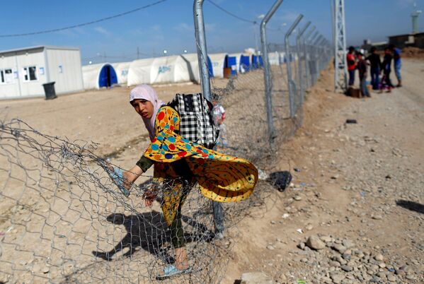 Беженка из Ирака перешагивает через забор, чтобы попасть в лагерь Хаммам аль-Алиль к югу от Мосула - Sputnik Lietuva