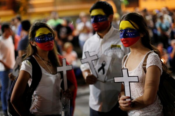 Сторонники оппозиции и студенты с лицами, выкрашенными в цвета венесуэльского национального флага, держат кресты во время бдения в знак уважения к жертвам насилия в Каракасе - Sputnik Lietuva