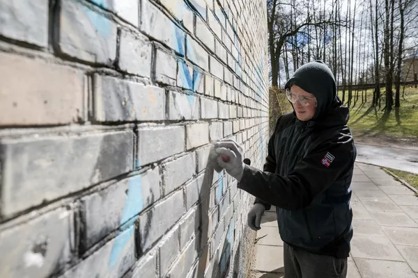 Доброволец смывает граффити со стены Доброволец смывает граффити со стены - Sputnik Lietuva