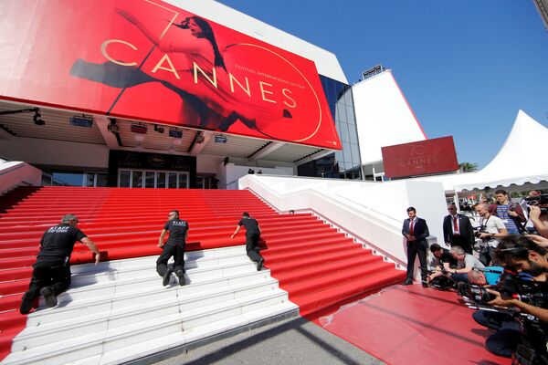 Рабочие разворачивают красный ковер перед главным входом Дворца фестиваля для церемонии открытия Каннского кинофестиваля - Sputnik Литва