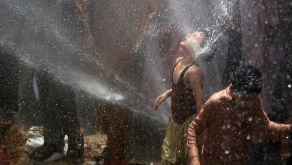 Мальчик спасается от жары в фонтане воды - Sputnik Литва