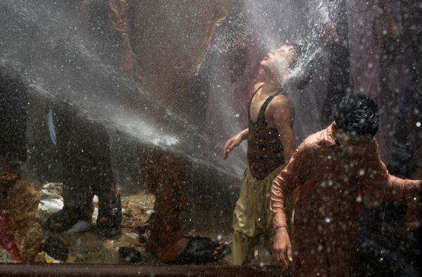 Мальчик спасается от жары в фонтане воды - Sputnik Lietuva