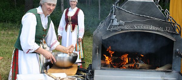 Женщины в литовских национальных костюмах готовятся к выпечке шакотиса Женщины в литовских национальных костюмах готовятся к выпечке шакотиса - Sputnik Lietuva
