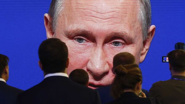 Владимир Путин на экране перед аудиторией - Sputnik Литва