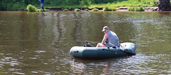 Рыбак в надувной лодке в деревне Минге - Sputnik Lietuva
