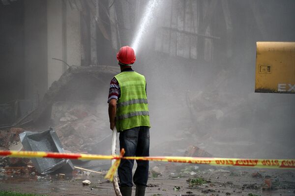 Работник компании генподрядчика с брандспойтом  - Sputnik Литва