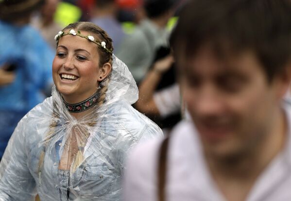 Молодая женщина проходит через главный вход во время сильного дождя на открытии 184-го фестиваля пива Октоберфест в Мюнхене, Германия. - Sputnik Литва