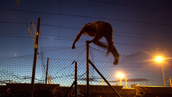 Мигрант перепрыгивает через забор в Кале, Франция - Sputnik Литва