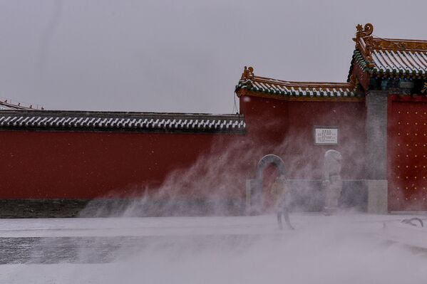 Китайский турист стоит у Императорского дворца во время снегопада в Шэньяне - Sputnik Литва