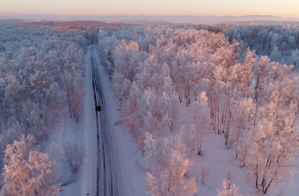 Машина едет по трассе вдоль заснеженного леса на закате, Красноярский край - Sputnik Литва