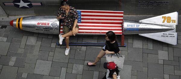 Посетители одного из торговых центров в Пекине возле скамейки в форме воздушной бомбы с флагом США, Китай  - Sputnik Литва