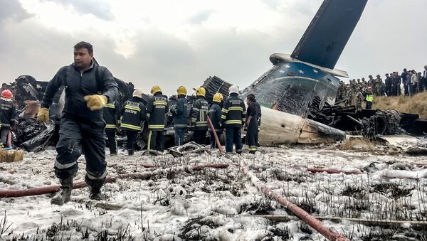 Непальские спасатели стоят возле пассажирского самолета из Бангладеш, который разбился в аэропорту в Катманду, Непал, в понедельник, 12 марта 2018 - Sputnik Литва