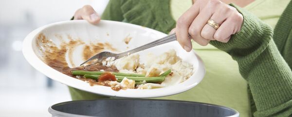 Женщина, счищающая пищевые остатки в мусорное ведро - Sputnik Литва