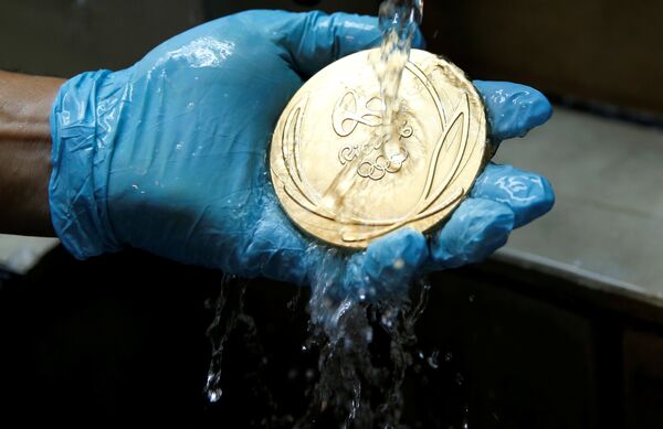 Работник очищает золотую медаль Олимпийских игр 2016 года в Рио-де-Жанейро, Бразилия - Sputnik Литва