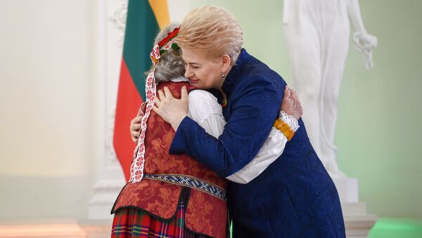 Президент Литвы Даля Грибаускайте обнимает кого-то в национальном литовском костюме - Sputnik Lietuva