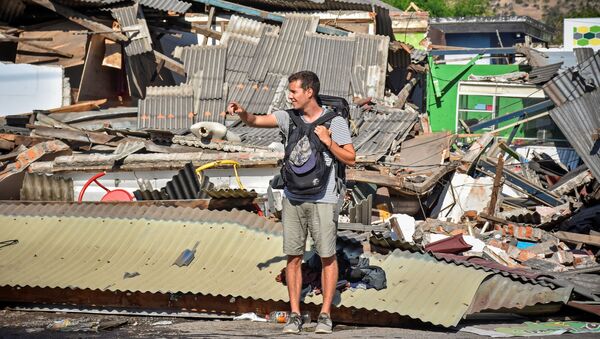 Иностранный турист ловит такси у разрушенной землетрясением  гостиницы в Ломбоке - Sputnik Lietuva