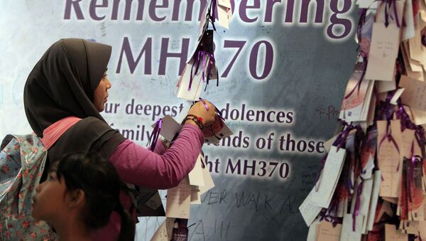Женщина привязывает карточку с сообщением для пассажиров пропавшего Боинга 777 рейса MH370 Малазийских авиалиний - Sputnik Lietuva