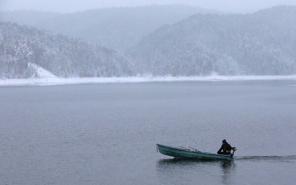 Мужчина едет на лодке через реку Енисей близ Красноярска. - Sputnik Литва