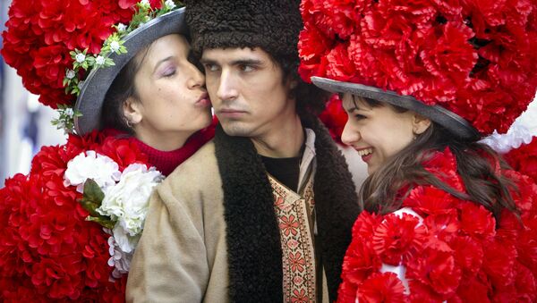 Юноша в традиционном румынском костюме в окружении девушек в цветочных нарядах в Бухаресте - Sputnik Литва