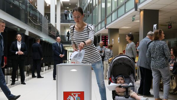 Женщина с ребенком голосует во время досрочного голосования второго тура президента Литвы, 21 мая 2019 года - Sputnik Литва