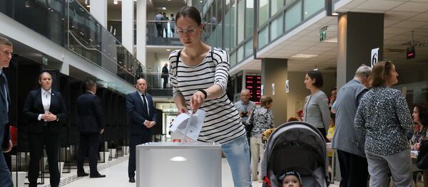Женщина с ребенком голосует во время досрочного голосования второго тура президента Литвы, 21 мая 2019 года - Sputnik Литва