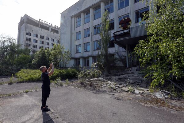 Посетитель фотографирует здание в заброшенном городе Припять, недалеко от Чернобыльской АЭС, Украина, 2 июня 2019 года - Sputnik Lietuva